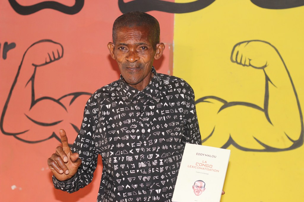 Eddy Malou, posant avec son livre La Congolexicomatisation